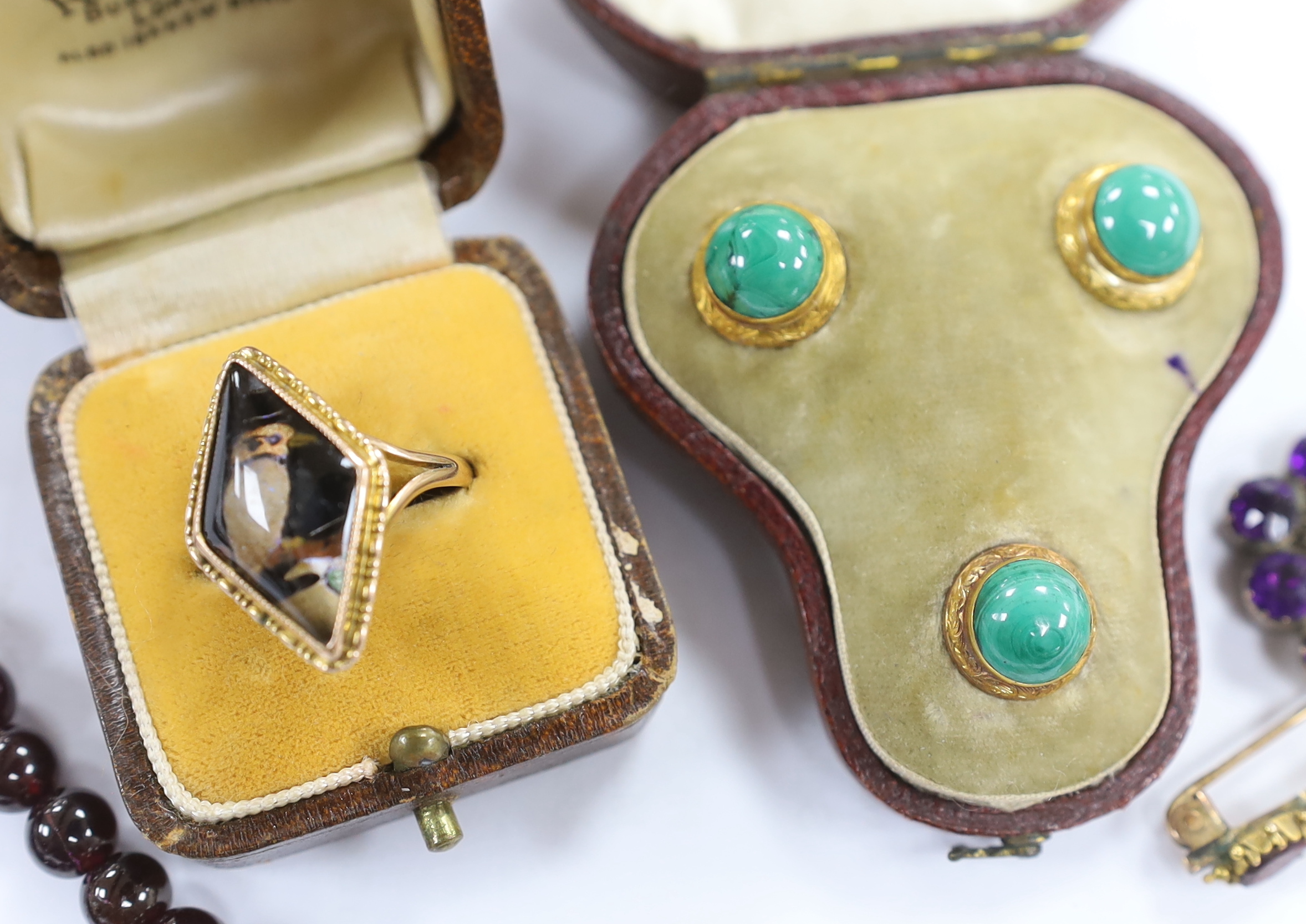 A Georgian amethyst paste and seed pearl set mourning brooch, with plaited hair, 27mm, a cased set of three Edwardian yellow metal and malachite set dress studs, a garnet bead necklace, brooch and a ring.